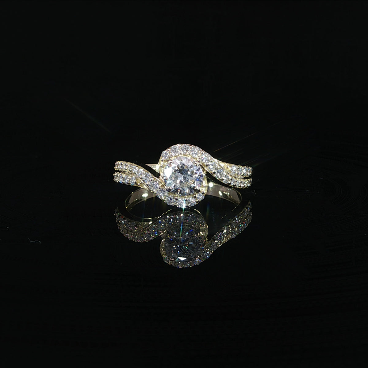 Front view of a round diamond bypass engagement ring in 14K yellow gold with a pavé-set band.