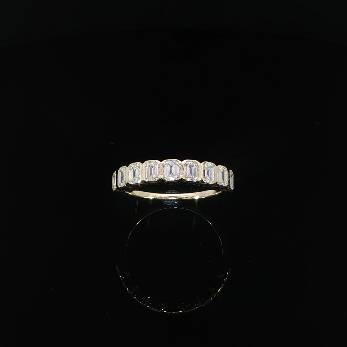 Angled view of a 1.14 CTW lab-grown diamond band in 14K yellow gold on a reflective black surface.