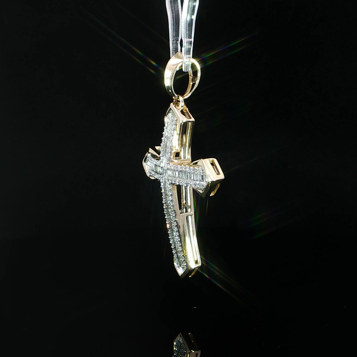 Angled view of a diamond cross pendant showing polished yellow gold sides and open setting details.
