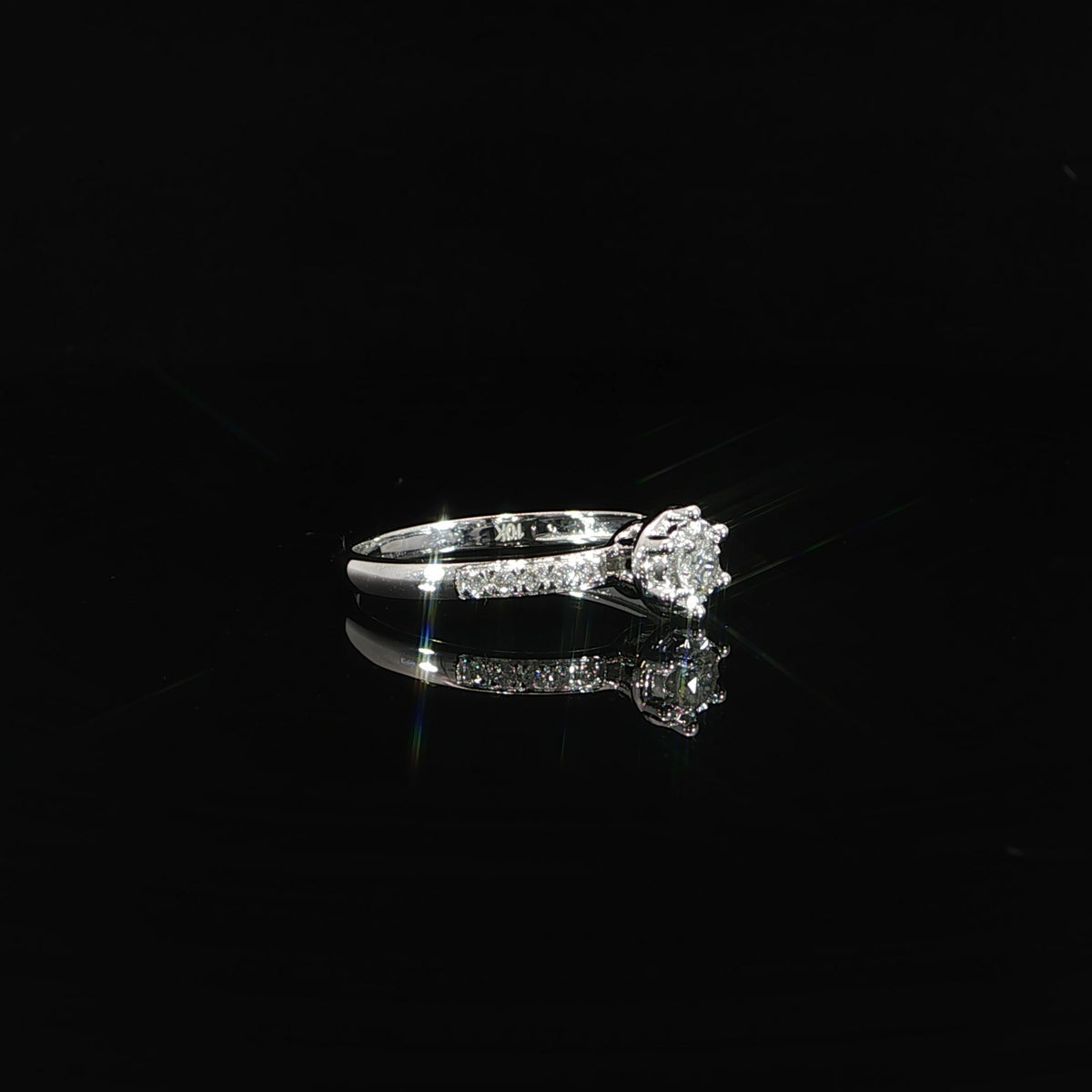 Side view of a 10K white gold 0.22 CTW round diamond illusion ring with diamonds along the shoulders.