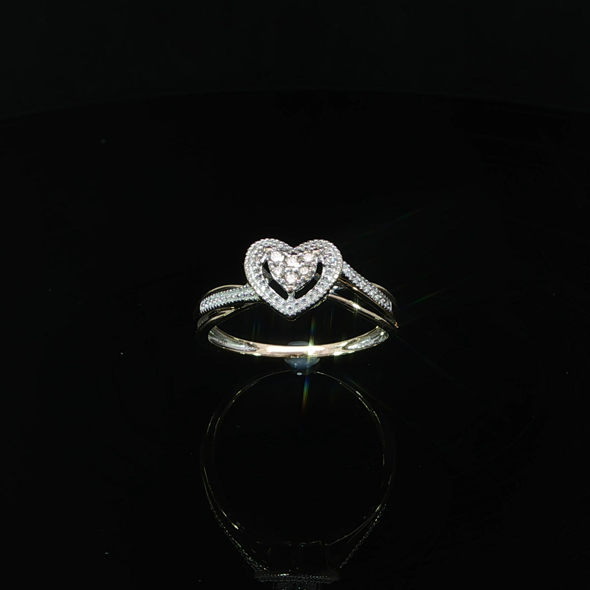 Tilted view of a 10K yellow gold 0.10 CTW heart ring with polished and diamond-accented split shoulders.