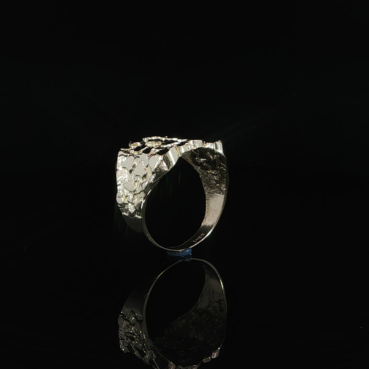 Raised nugget texture and polished shoulders of a 10K yellow gold ring, shown from the side.