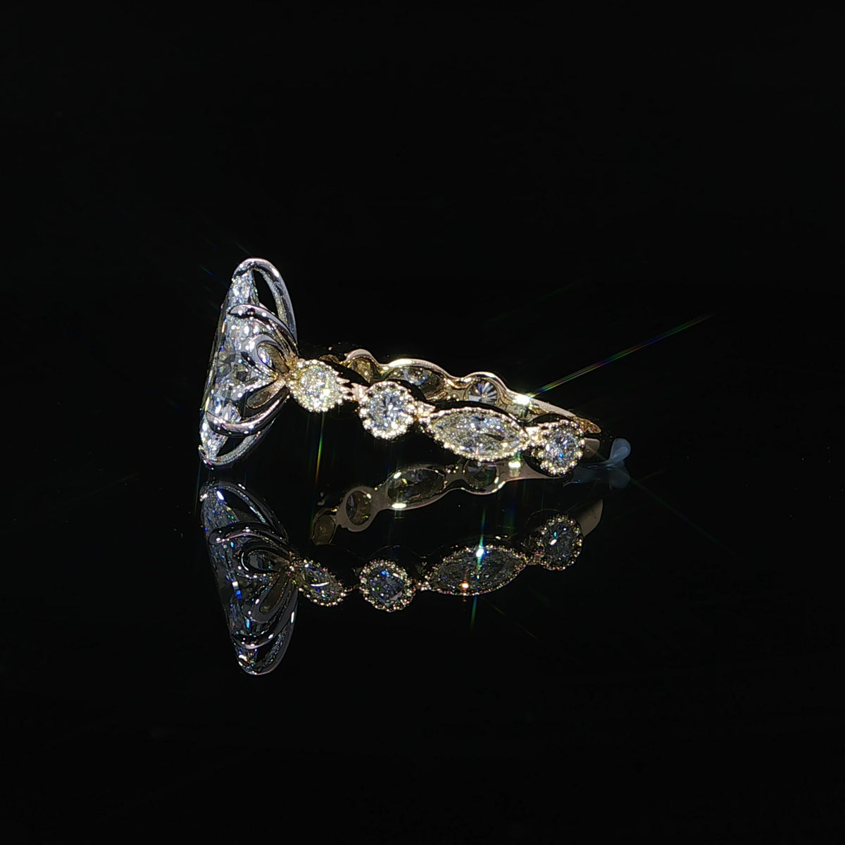 Side view of a marquise diamond ring with bezel-set band diamonds and an open gallery