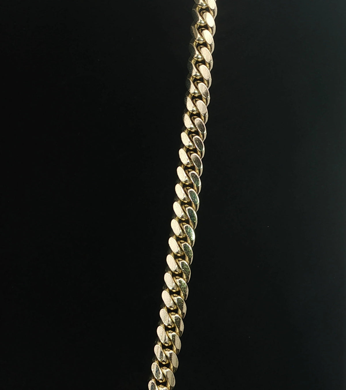 Close-up of polished interlocking links on a 14K yellow gold Miami Cuban chain