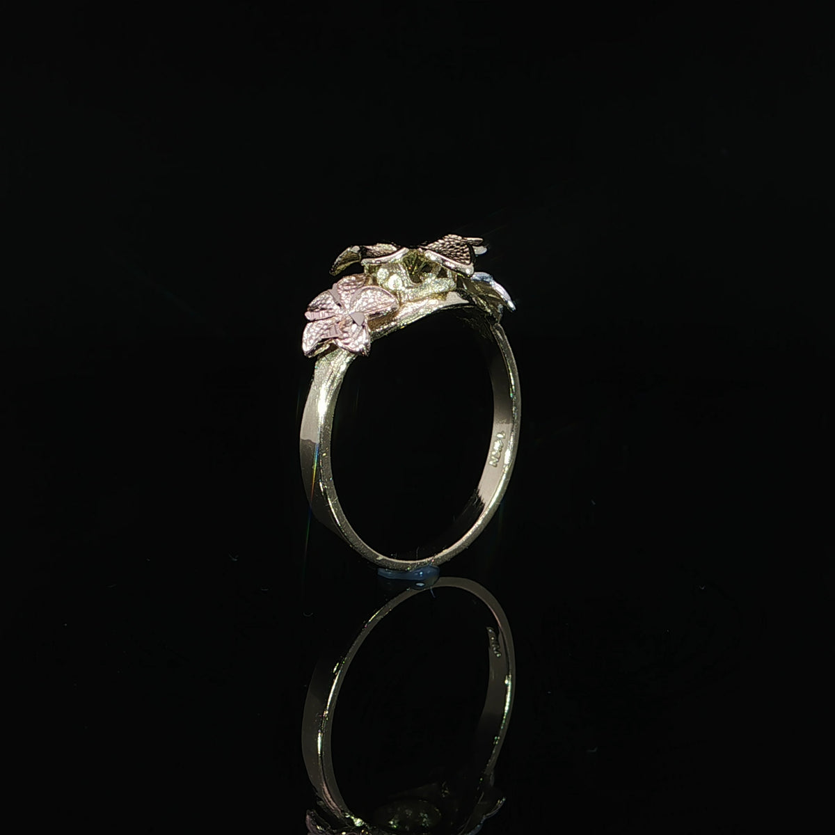 Side profile of a 14K gold plumeria ring showing raised flowers and the band