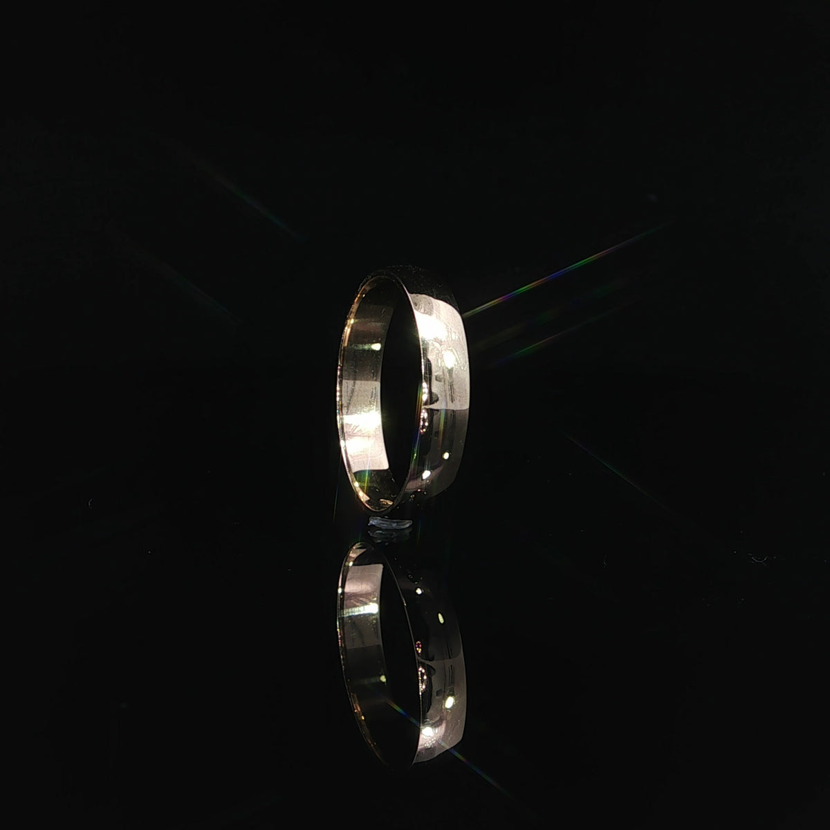 Close-up of a 14K solid gold wedding band displaying its smooth, mirror-like polished finish and gently curved outer surface.