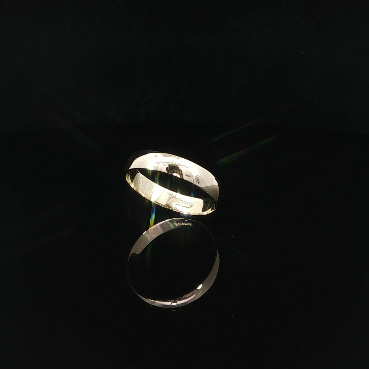 Three-quarter angled view of a 14K solid gold wedding band highlighting its 4mm width, reflective finish, and smooth inner surface.