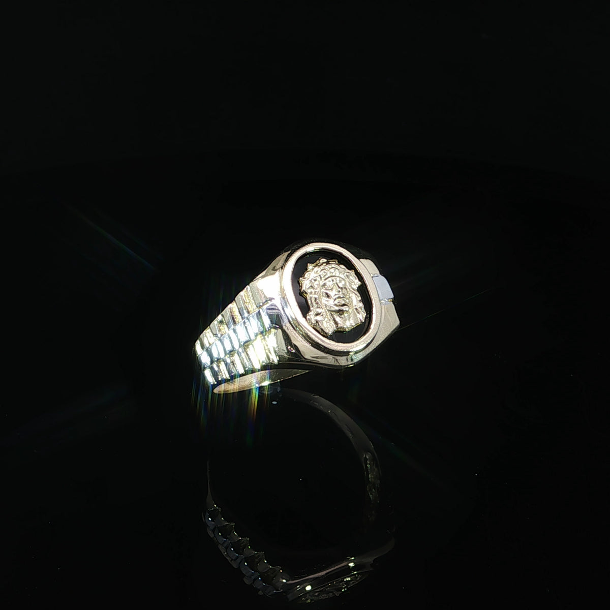 Three-quarter angled view of a 14K two-tone gold Jesus Christ signet ring highlighting the raised oval portrait, polished gold frame, and decorative striped shoulders.