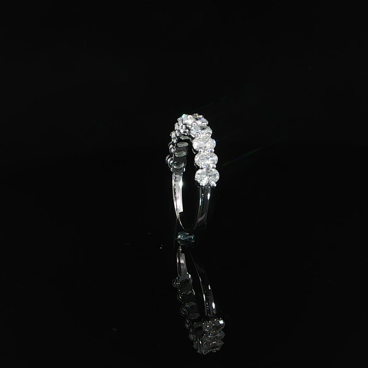 Side profile showing the oval diamond settings and polished lower shank of a 14K white gold band.