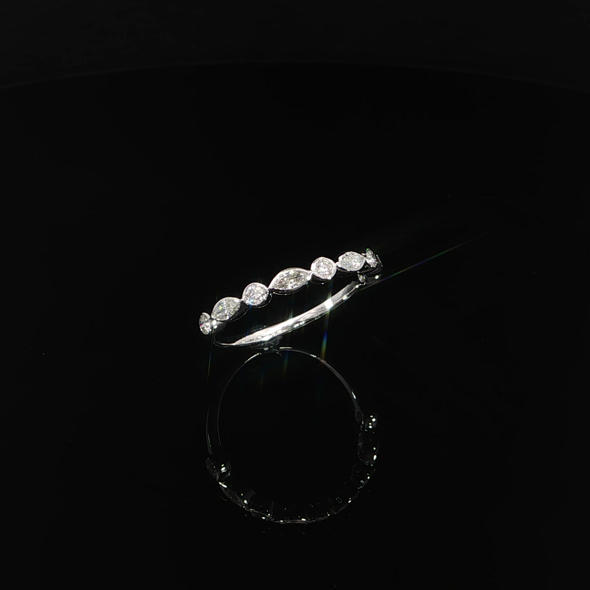 Angled view of alternating marquise and round diamonds framed by smooth white gold bezels.