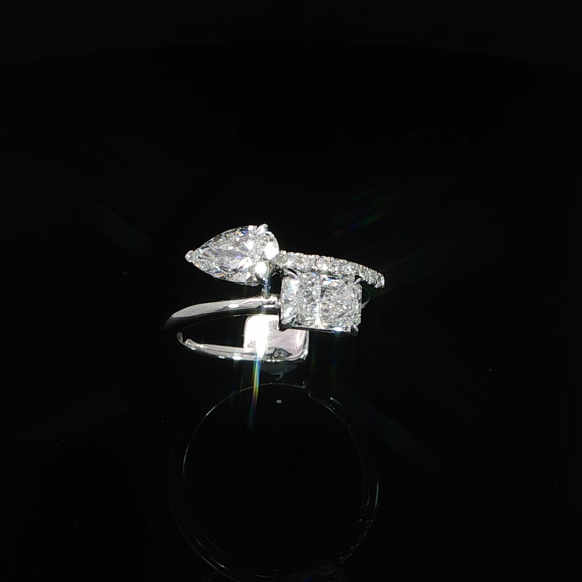 Angled view of a two-stone diamond engagement ring with radiant and pear shaped center stones.