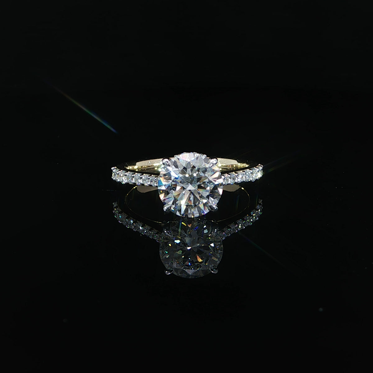 Front view of a round diamond engagement ring featuring raised cathedral shoulders and a diamond band.