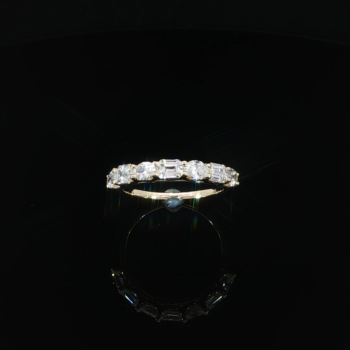 Front view of a 14K yellow gold seven-stone band with alternating emerald-cut and oval diamonds.