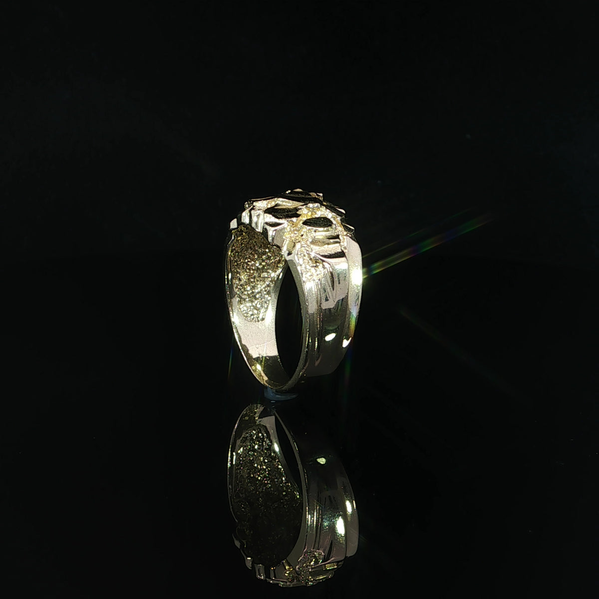 Side detail of a 14K yellow gold nugget ring showing its smooth polished tapered shank and contrasting irregular diamond-cut top.