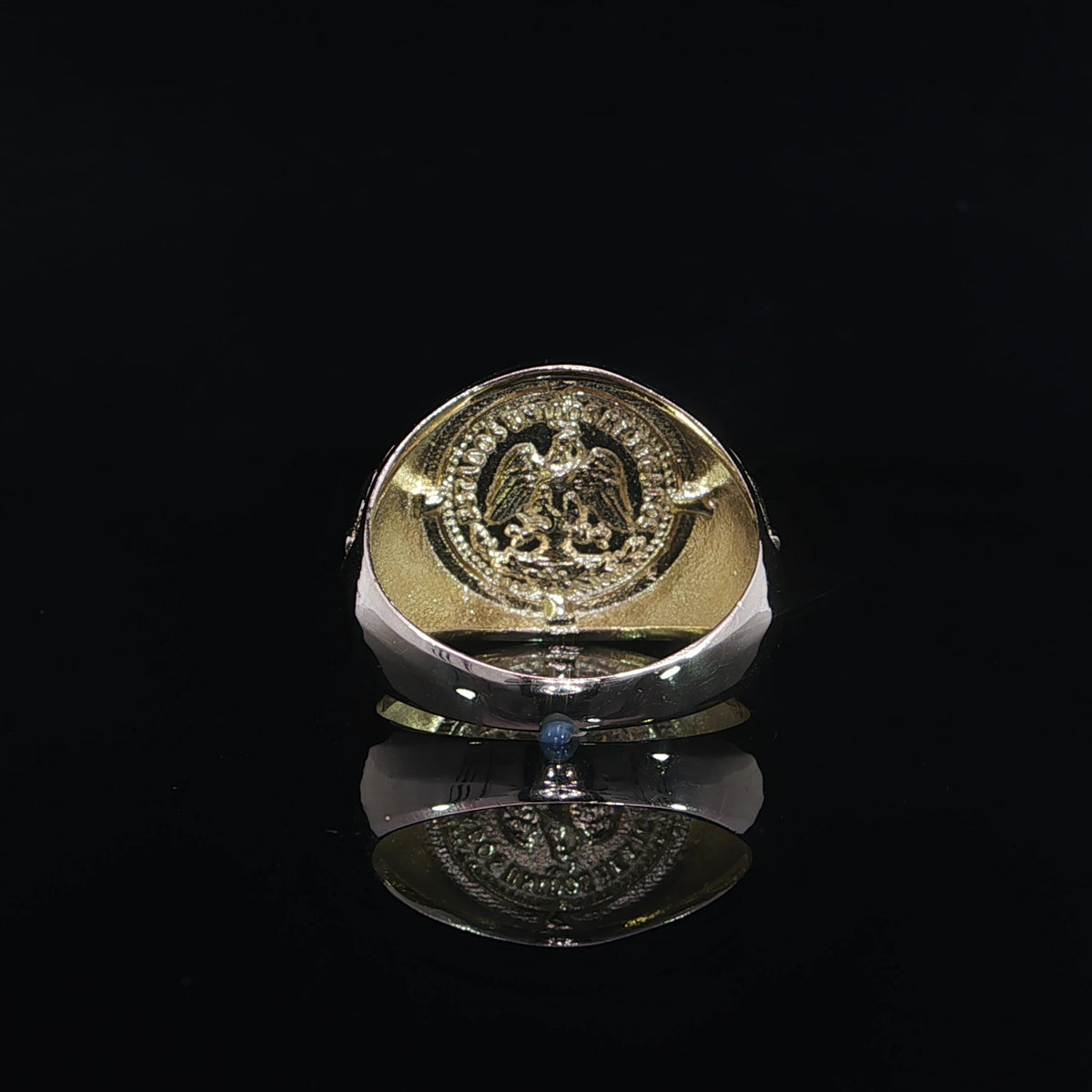 Interior view of a Centenario-inspired gold ring showing an eagle emblem beneath the round face and a polished band.