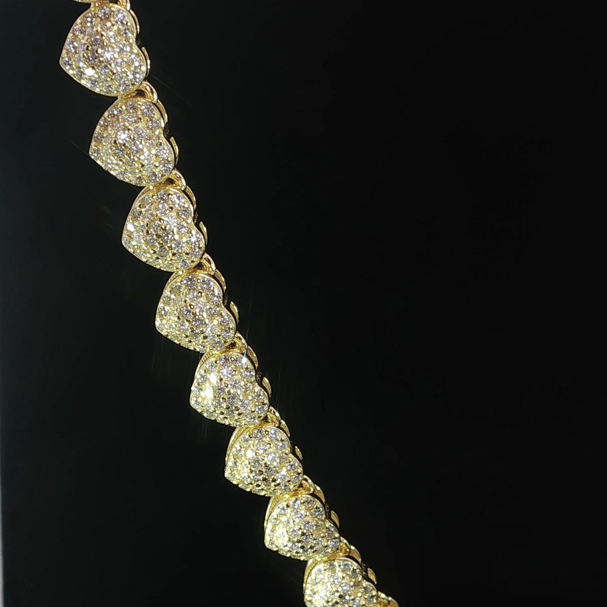 Close-up of petite moissanite heart links with halo detailing in gold plated sterling silver