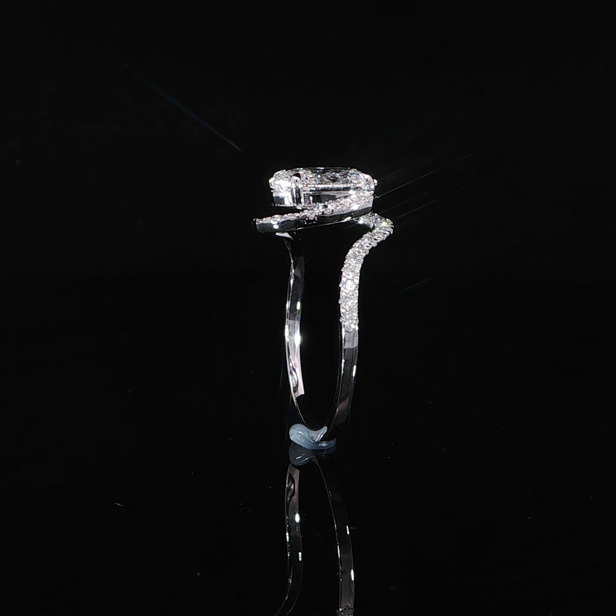 Close view of the pavé diamond bypass band curving around the oval halo setting.