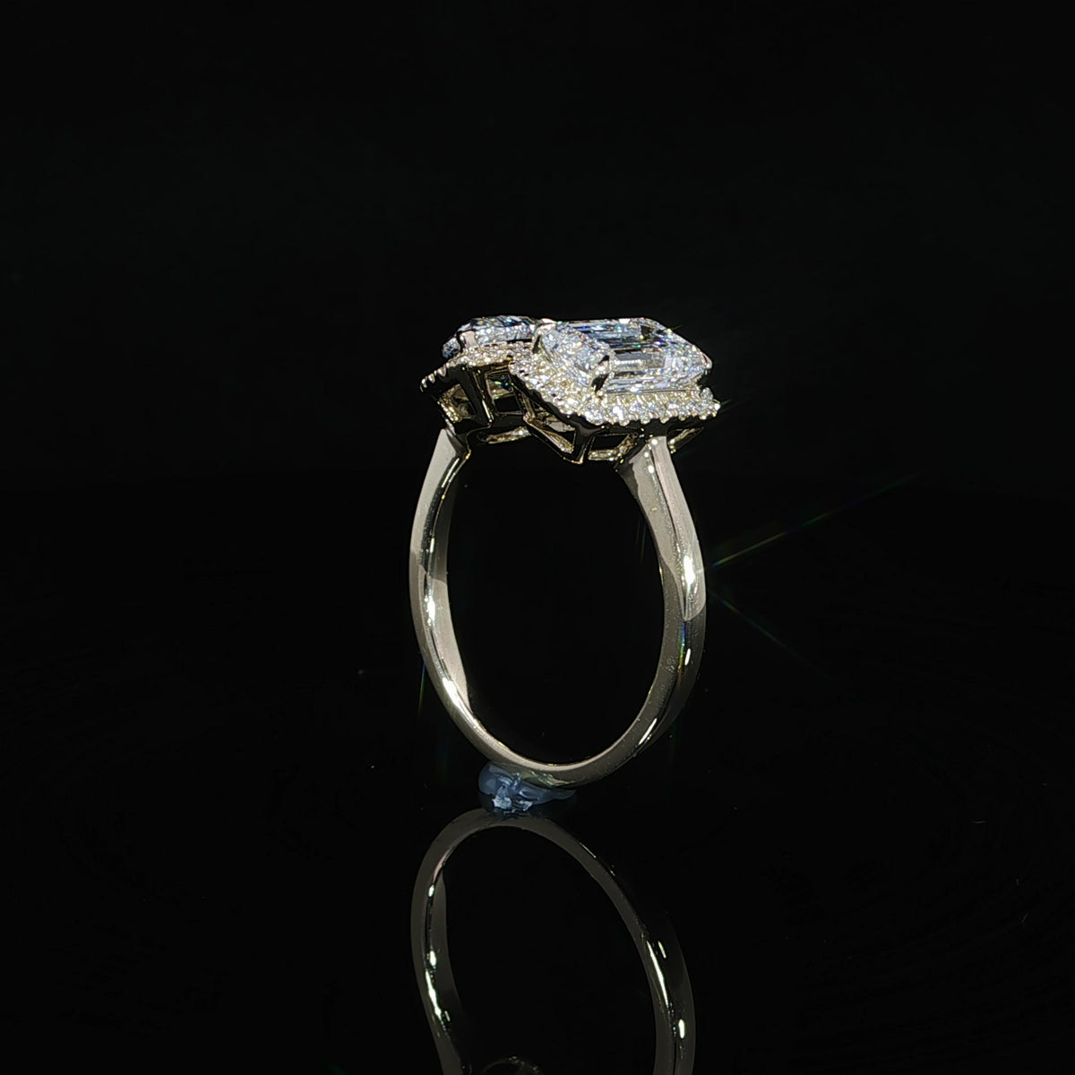 Detailed view of emerald cut and pear shaped diamonds framed by halo settings in yellow gold.