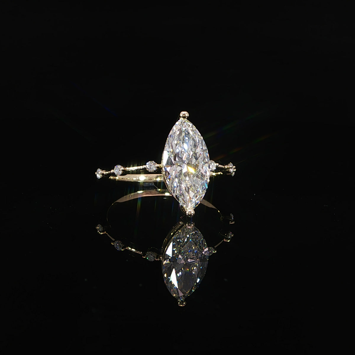 Angled view of a marquise diamond engagement ring with spaced diamonds along the yellow gold band.