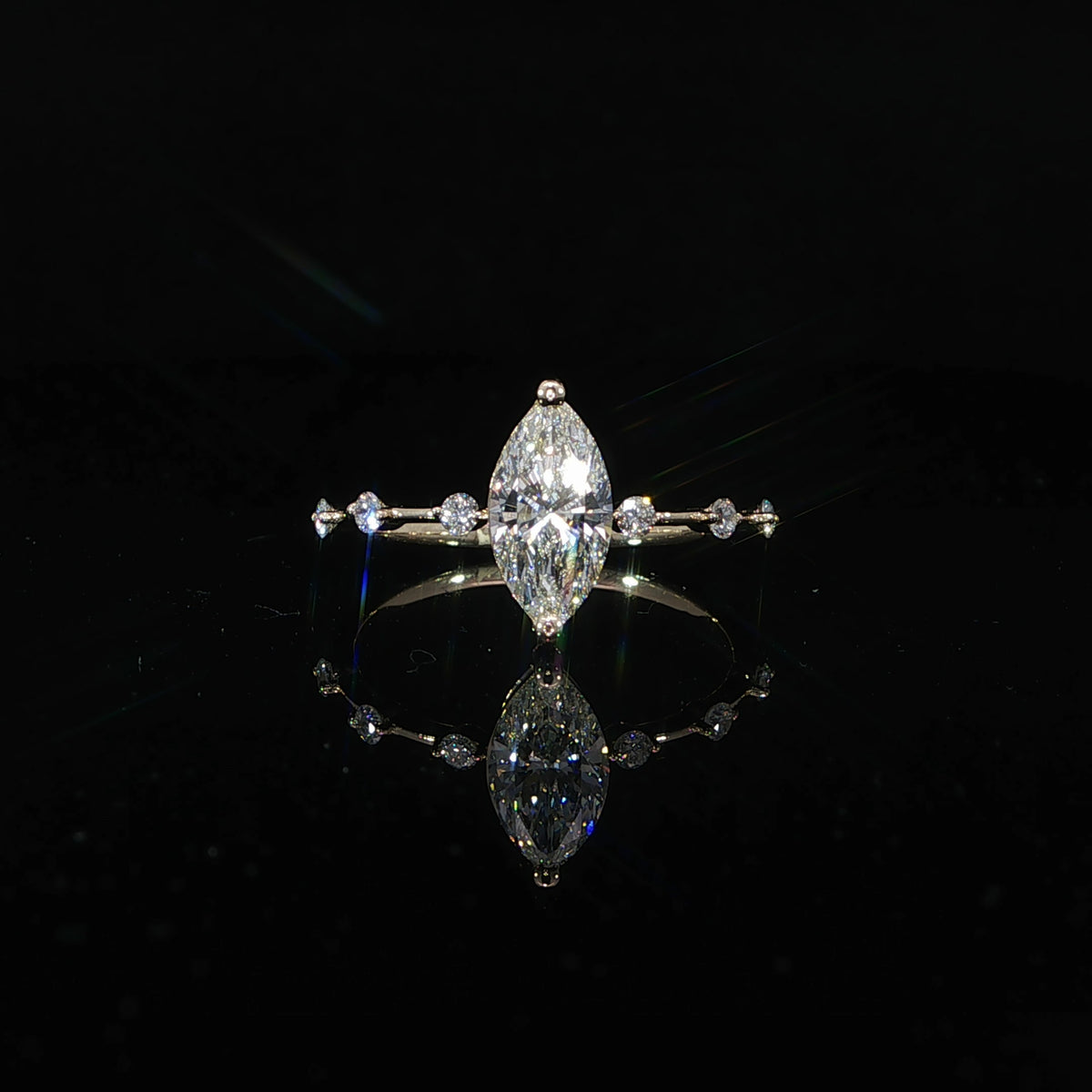 Front view of a marquise diamond engagement ring featuring a delicate diamond station band.