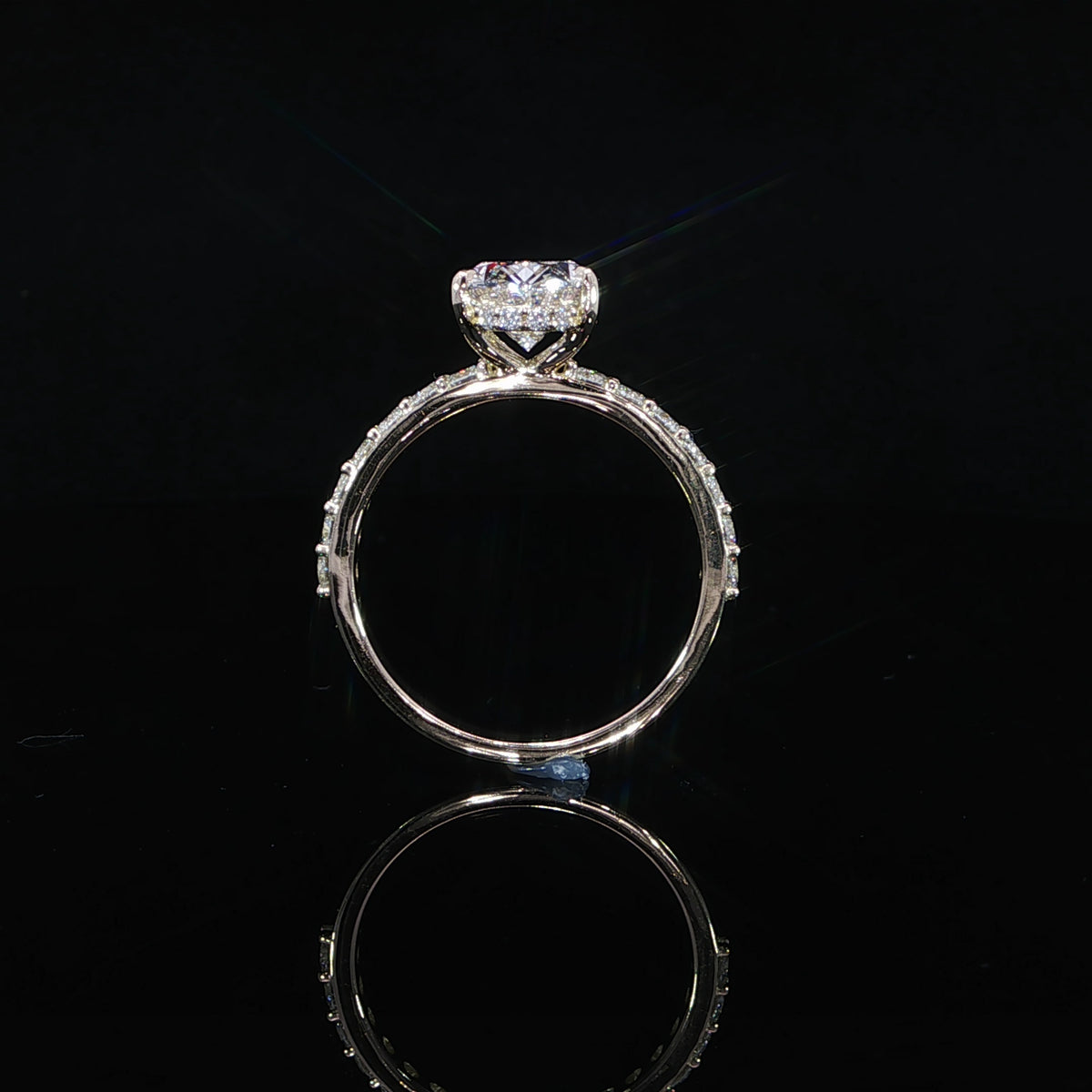 Modern oval diamond engagement ring with a hidden halo and diamond-accented yellow gold band.