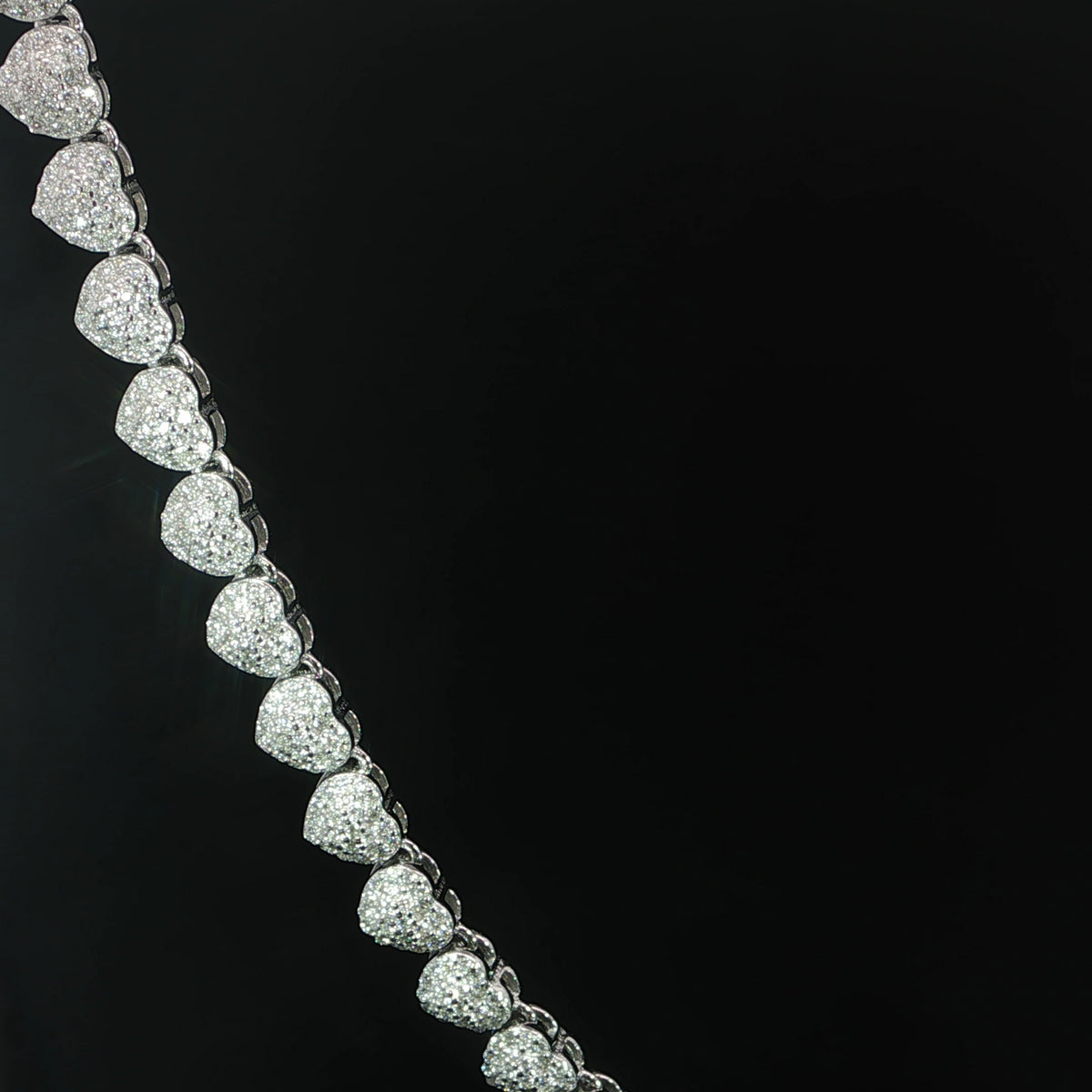 Close-up of petite moissanite heart links with halo detailing in sterling silver