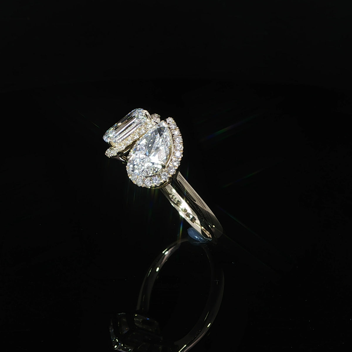 Open band Toi et Moi engagement ring with emerald cut and pear shaped diamonds in 14K yellow gold.