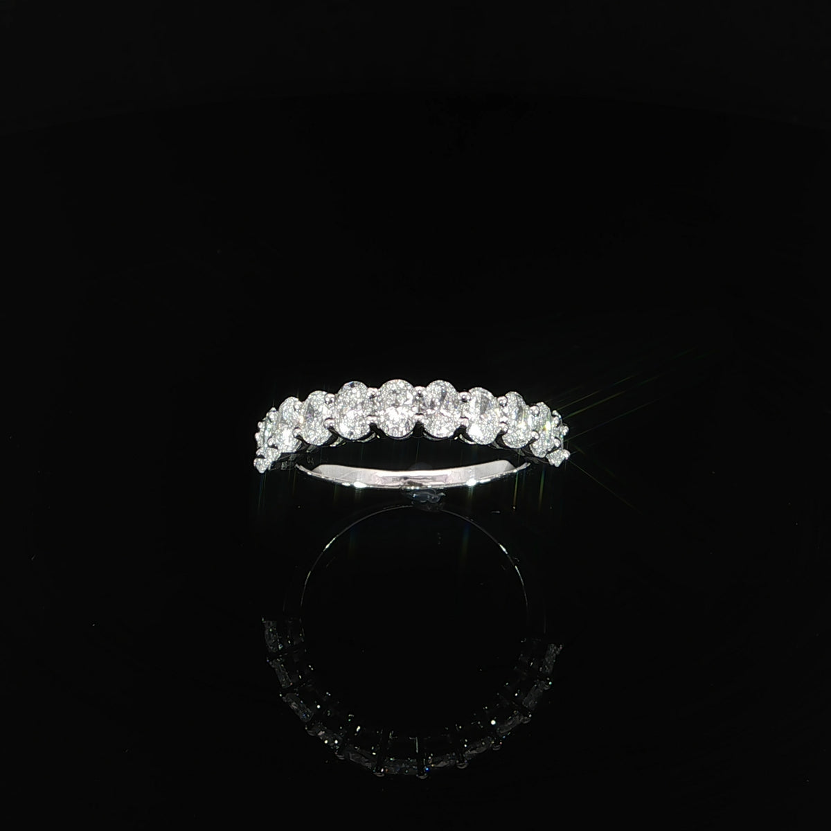 Raised front view of an oval diamond half eternity band with a polished gold shank.