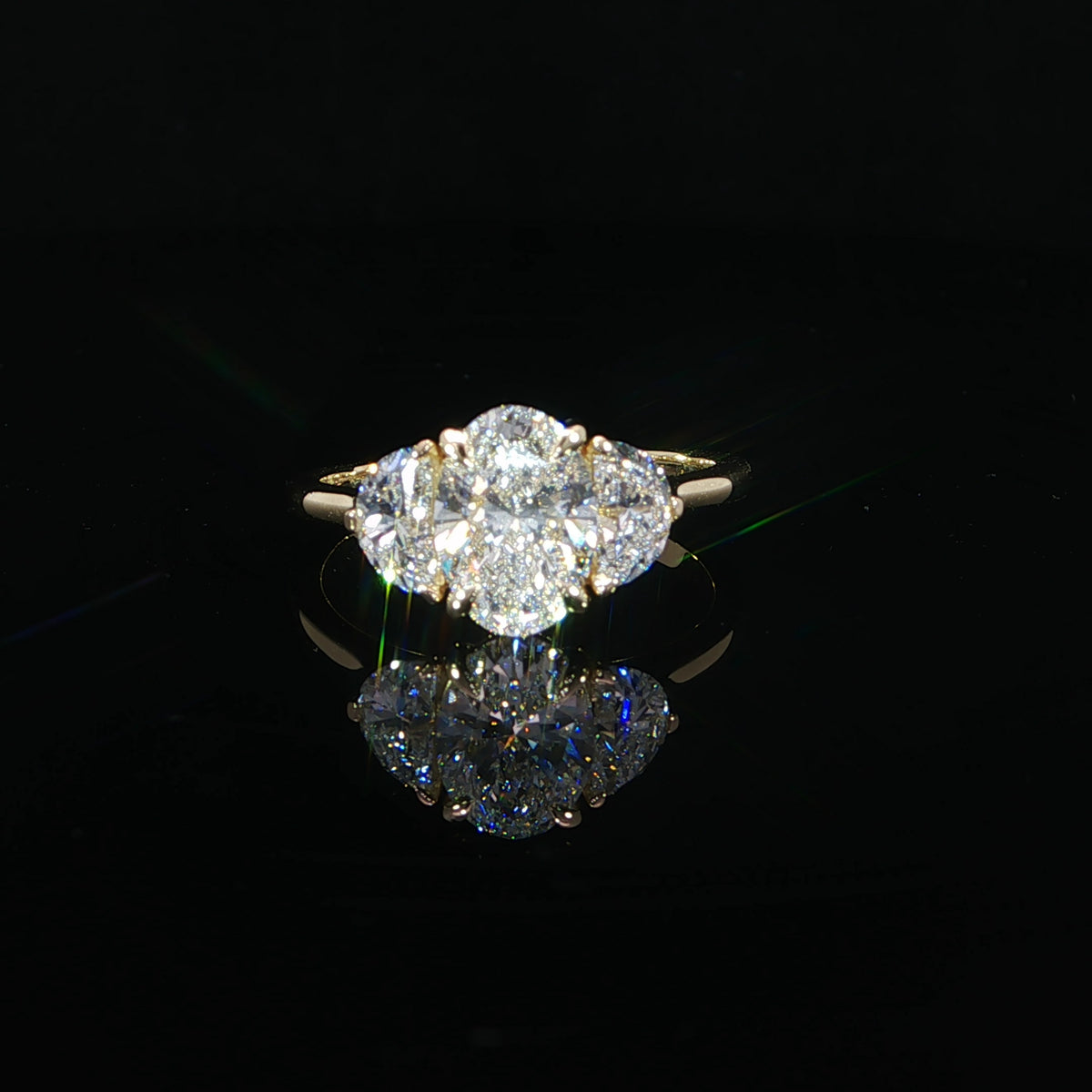 Front view of an oval diamond engagement ring framed by two half-moon diamonds.