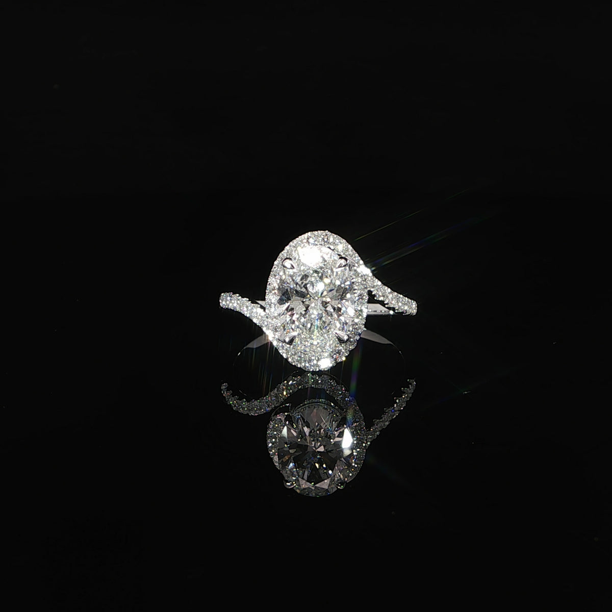 Front view of an oval diamond engagement ring framed by a sparkling halo and bypass band.