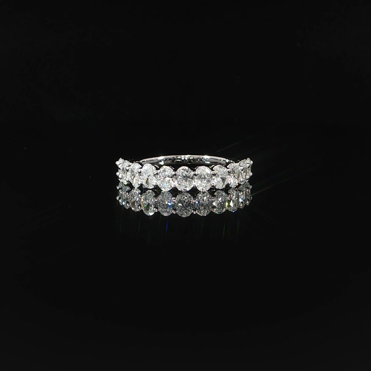 Front view of a 1.48 CTW oval lab-grown diamond band on a reflective black surface.