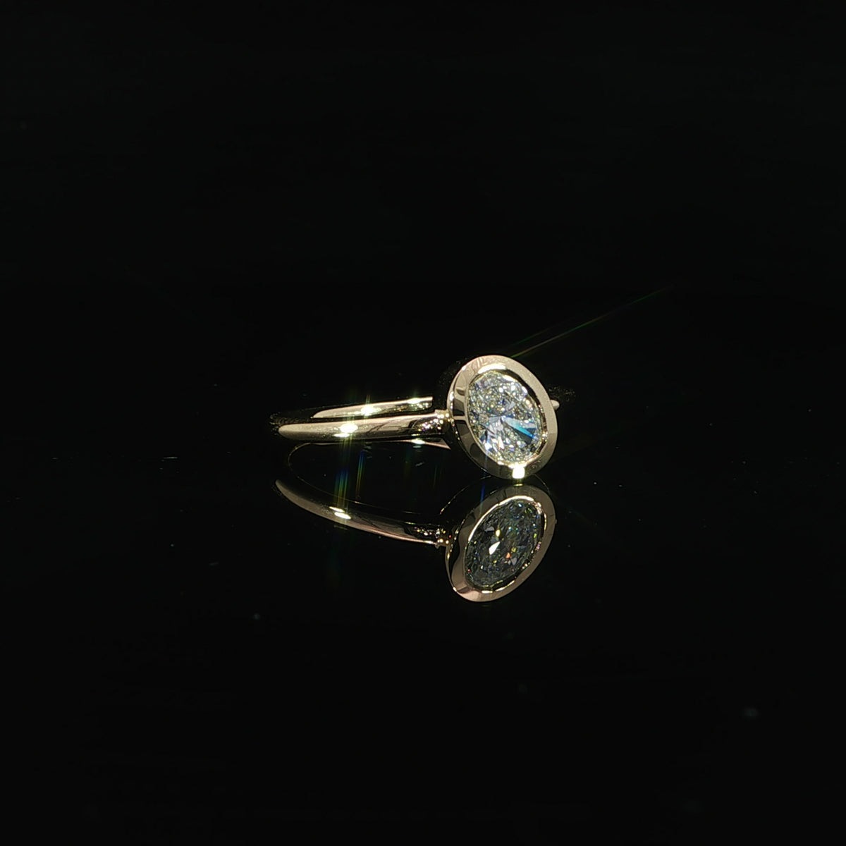 Oval lab grown diamond engagement ring with a sleek full bezel setting in 14K yellow gold.