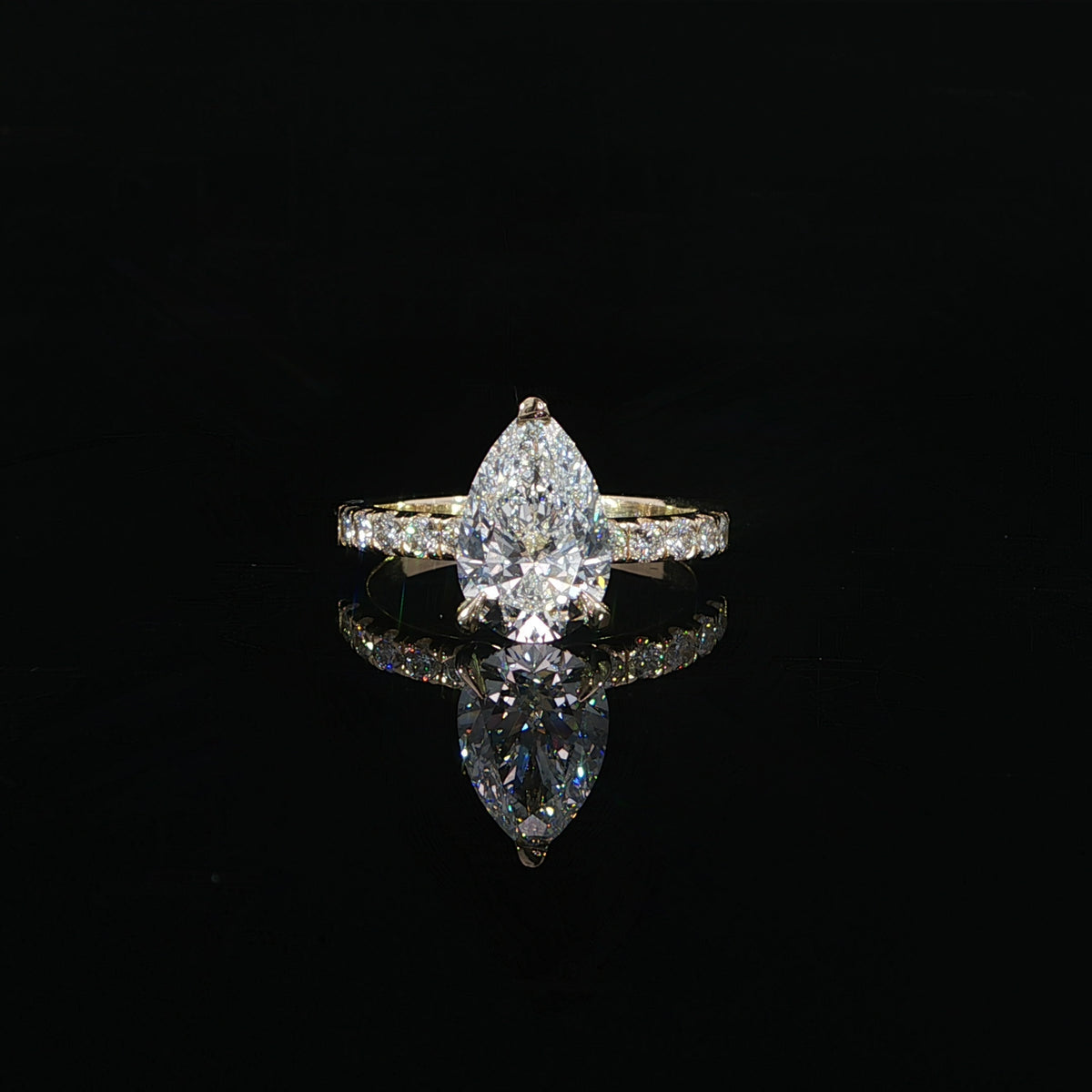 Front view of a pear-shaped diamond solitaire-style engagement ring in polished yellow gold.