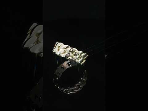 Angled view of a 14K yellow gold Cuban chain ring highlighting the open spaces between its raised interlocking links and the polished band underneath.