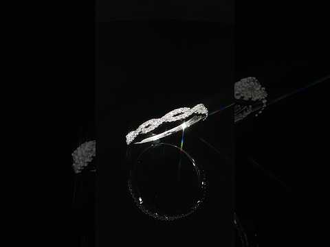 Angled profile of a modern 14K white gold twisted diamond ring featuring polished gold curves and pavé-set diamond accents.