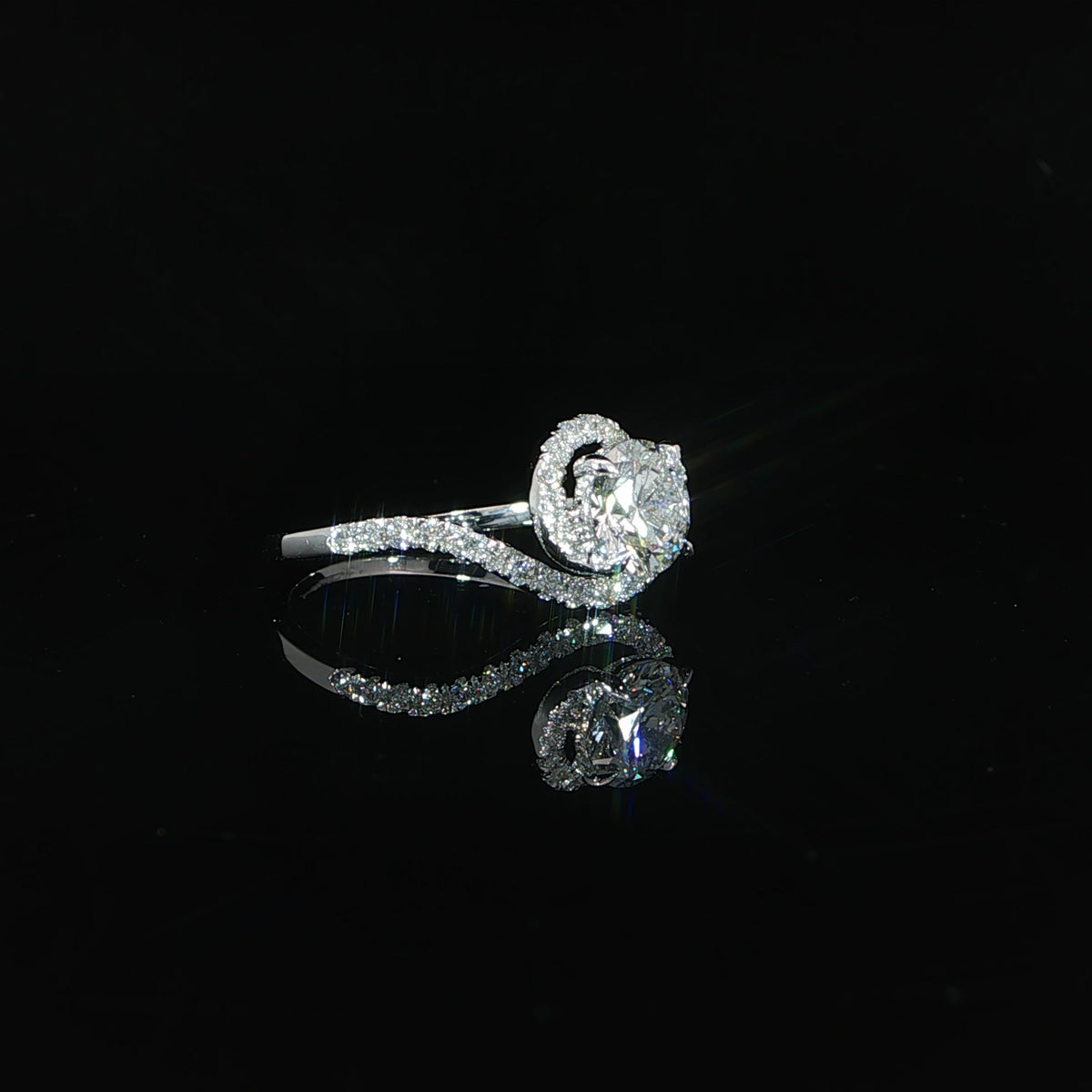 White gold ring resting on its side, showing the round center diamond and sweeping bypass band.