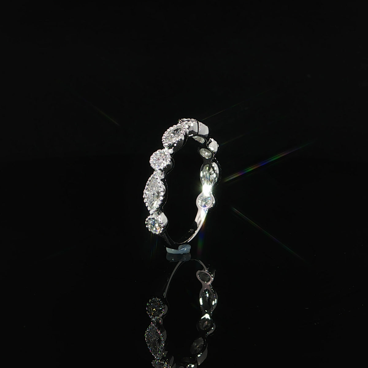 Upright side view of a white gold diamond band showing polished bezel walls and a slender lower shank.