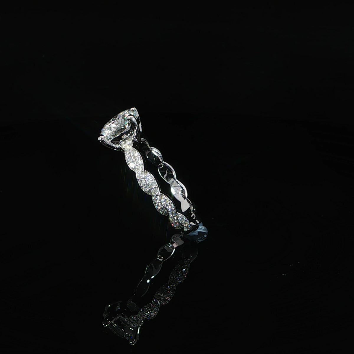 Diagonal view showing the pavé twists along the band and the open setting beneath the round diamond.