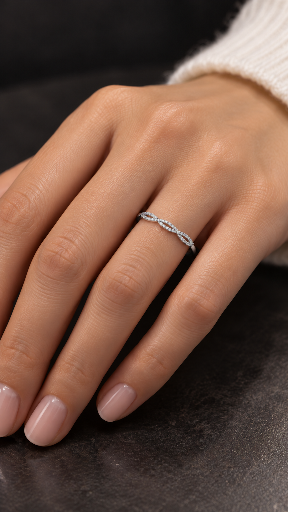 Model wearing white gold diamond band with intertwined strands forming an open twist pattern.