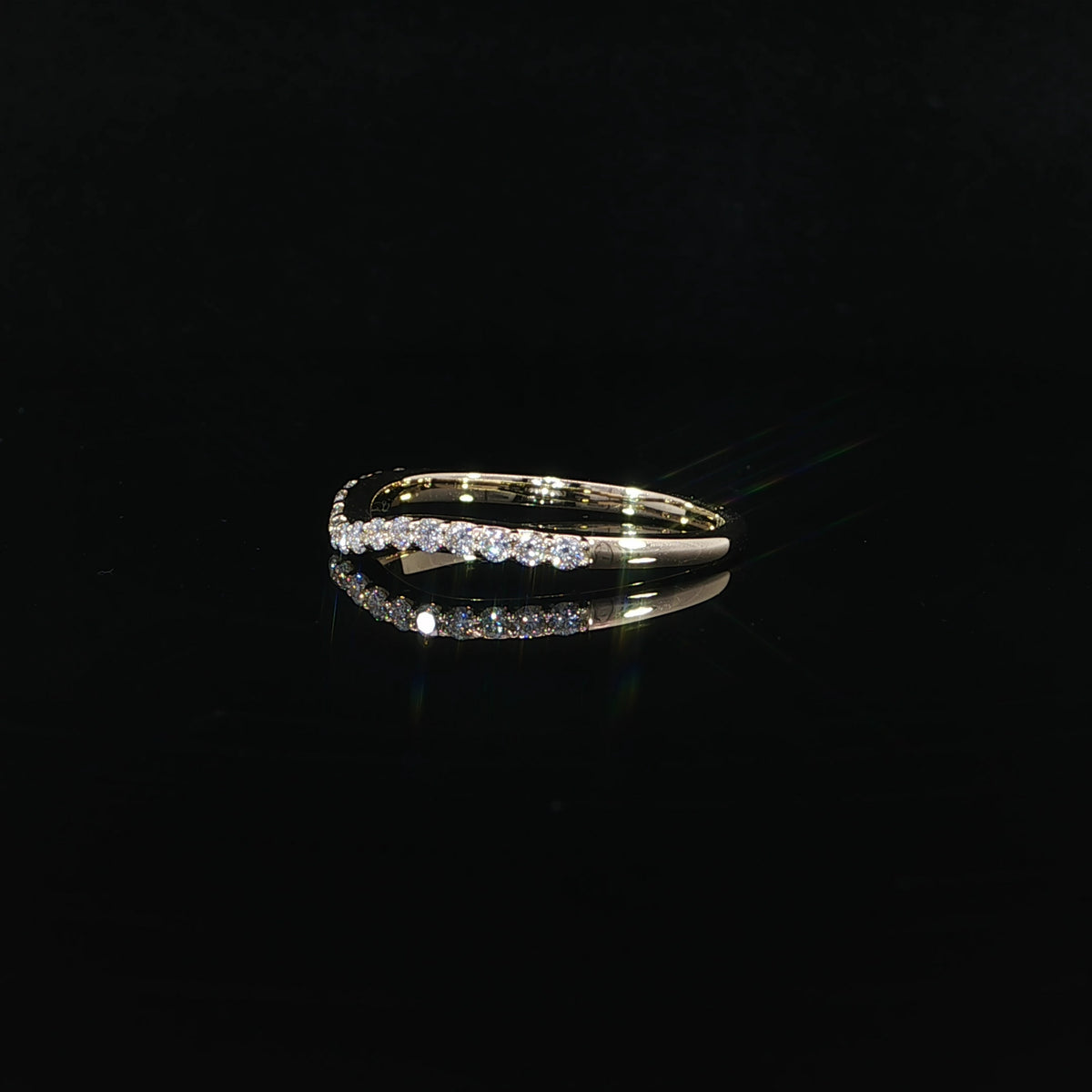 Side angle showing the diamond row and polished yellow gold shoulders of a contour band.
