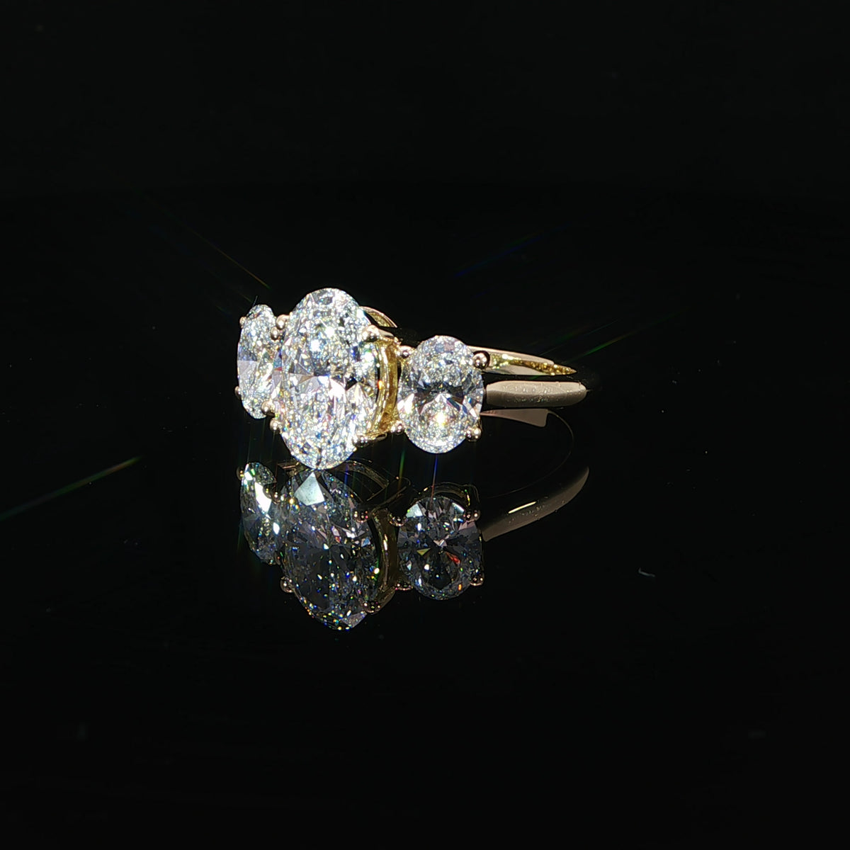 Side view of the yellow gold prong settings supporting the oval center and side diamond.