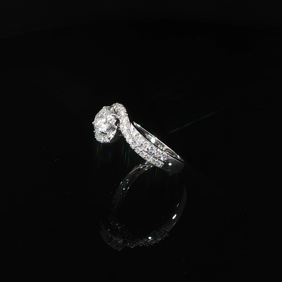 Angled view of a 0.50 carat round diamond ring with a curved pavé bypass design in 14K white gold.