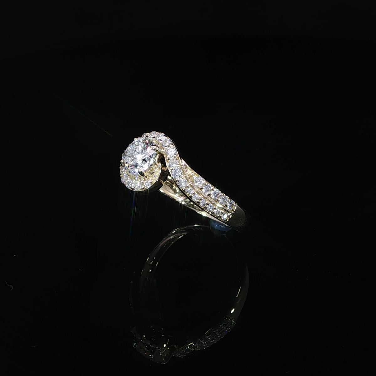 Angled view of a 0.50 carat round diamond ring with a curved pavé bypass design in yellow gold.