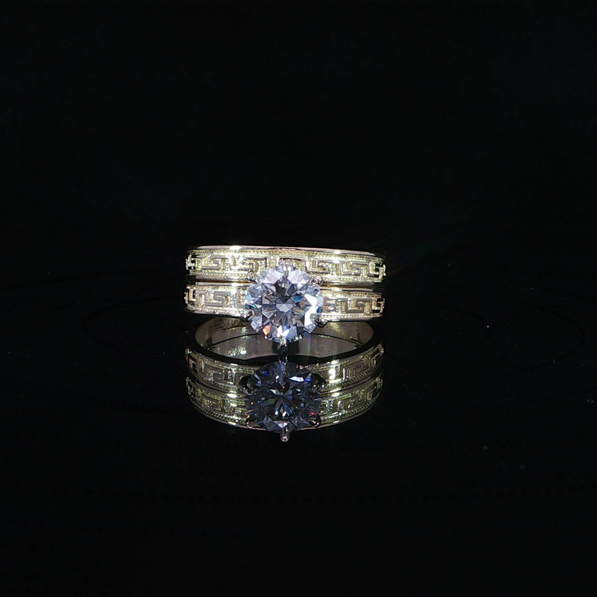 10K yellow gold engraved wedding set with a 1.21 CT round center diamond reflected on a black surface.
