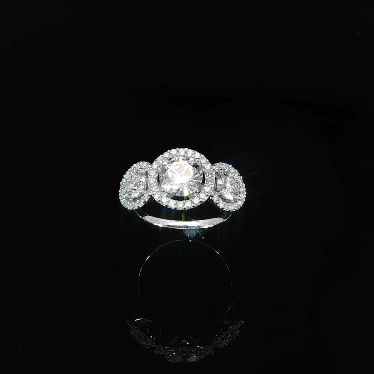 Front angle of a three-stone halo ring with a 1.50 carat round lab-grown center diamond