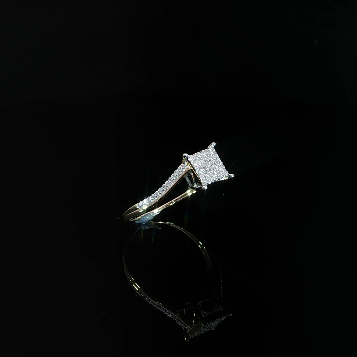 Diagonal view of a 0.11 CTW diamond cluster ring with a raised square head and yellow gold band.