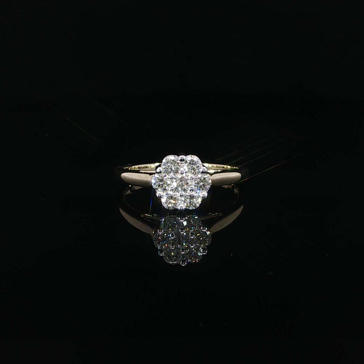 A 10K yellow gold 0.50 CTW natural diamond cluster ring resting above its reflection on a black surface.