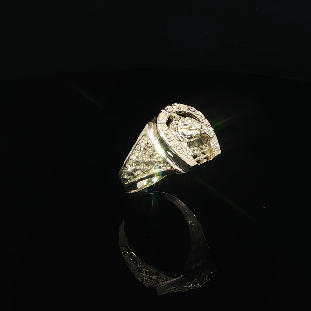 Angled view of a 14K gold equestrian signet ring with textured shoulder panels and polished borders.