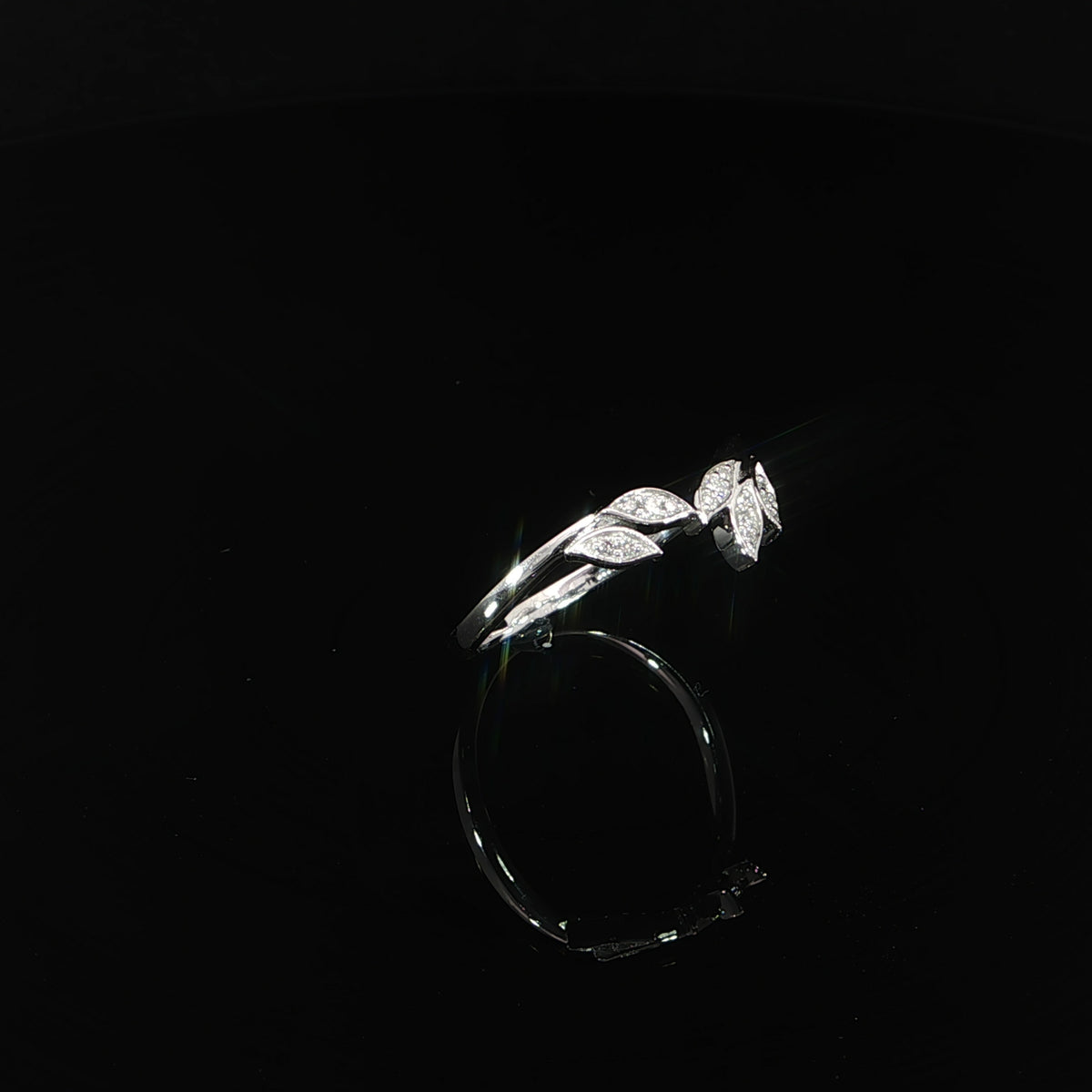 Angled view of a 14K white gold leaf ring with a slender polished shank and diamond-accented foliage.