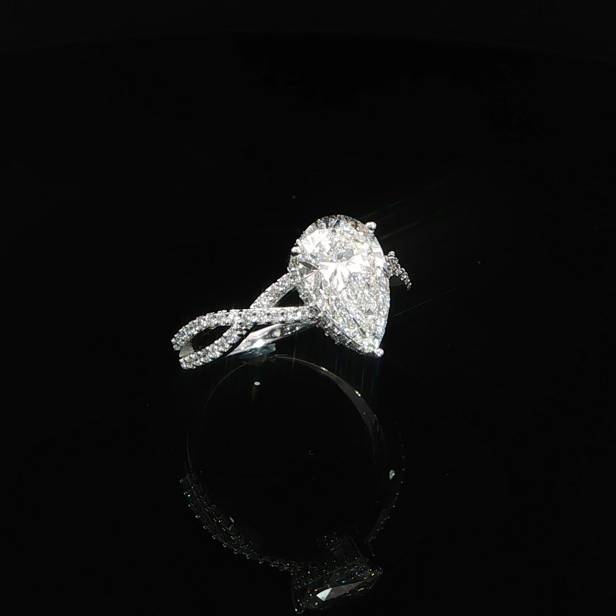 Angled view of a 14K gold engagement ring with a pear center diamond and sculptural twist band.